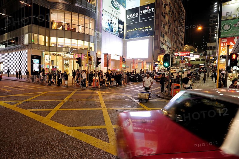 A red taxi driving on a street in Tsim Sha Tsui in the evening