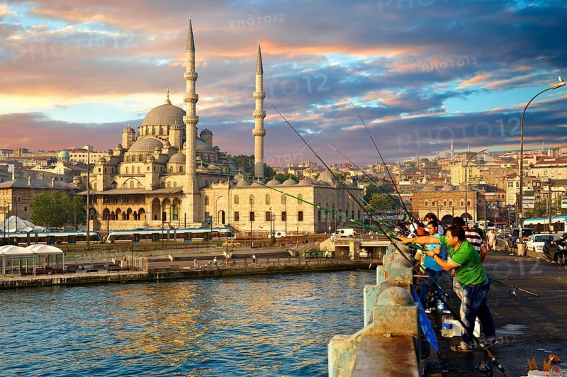 Fisherman on the Galata bridge fishing in the Golden Horn next to The Yeni Camii