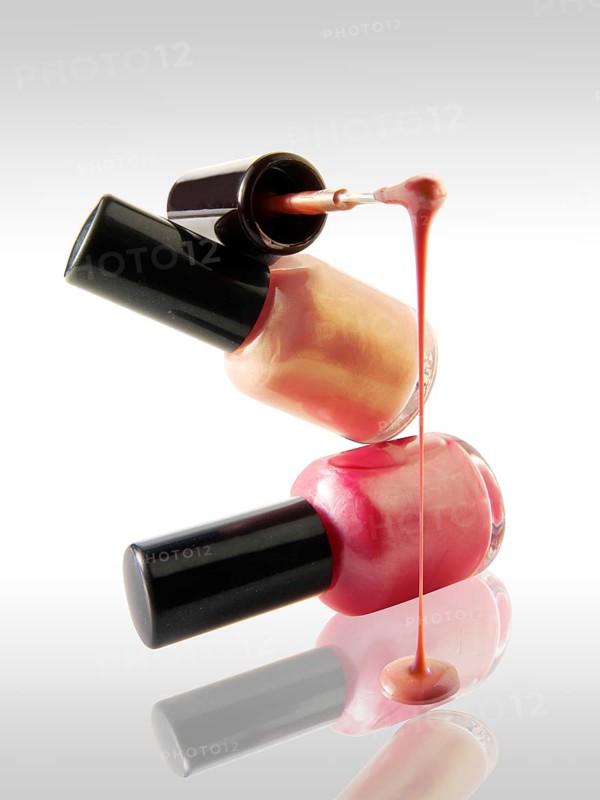 Pink nail varnish dripping from a nail varnish brush balanced on a nail varnish bottle