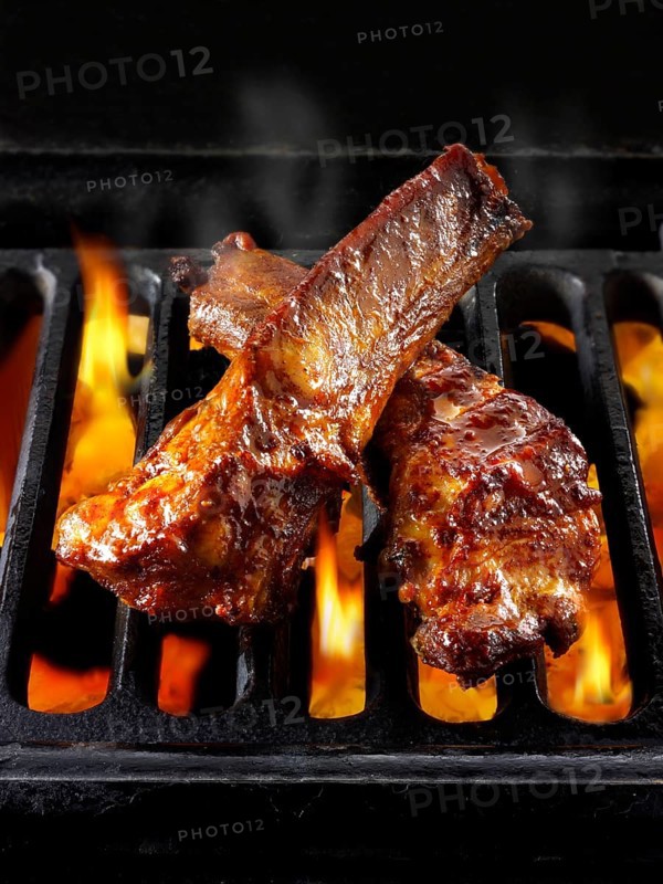BBQ spare ribs being cooked over open flames