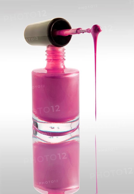 Pink nail varnish dripping from a nail varnish brush balanced on a nail varnish bottle