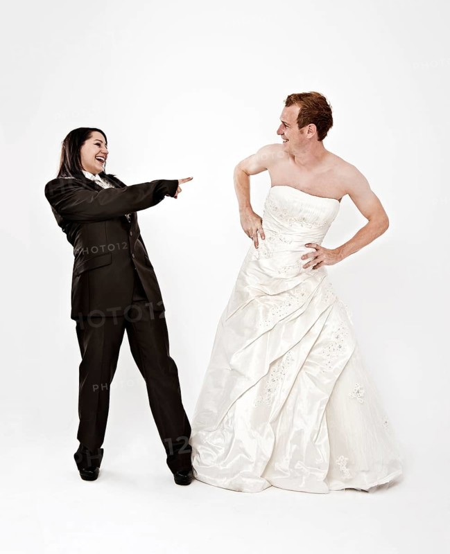 Bride wearing a suit laughing at a groom wearing a wedding dress