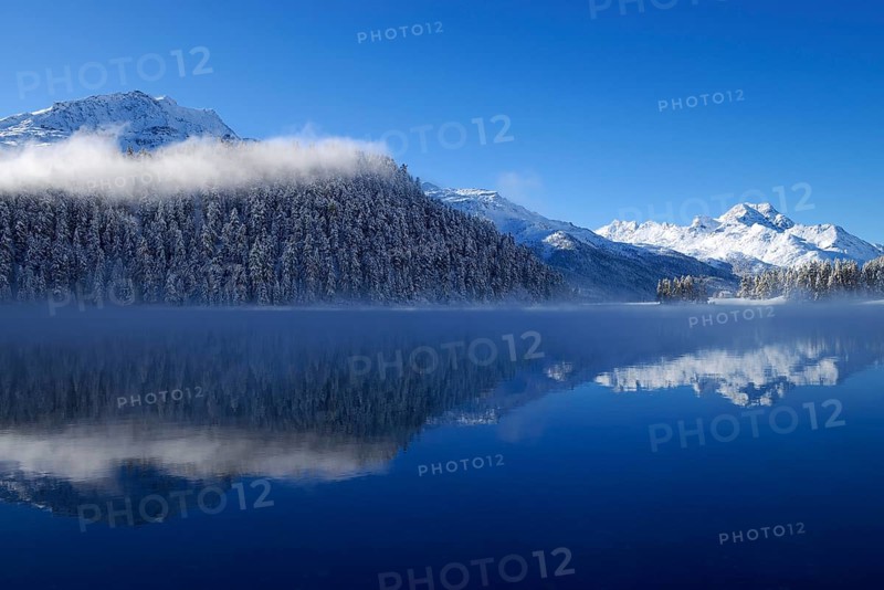 Snowy Piz da la Margna mountain being reflected in lake Champferersee