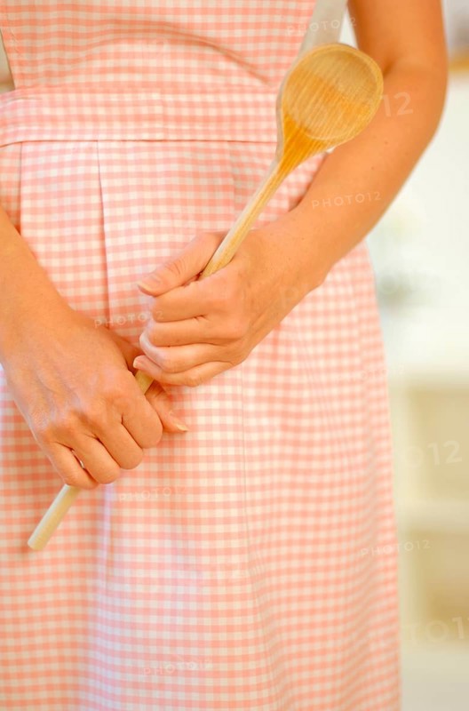 Housewife wearing an apron and holding a wooden spoon