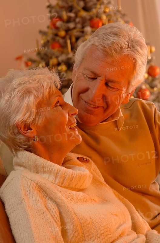 Mature couple in love sitting in front of a Christmas tree