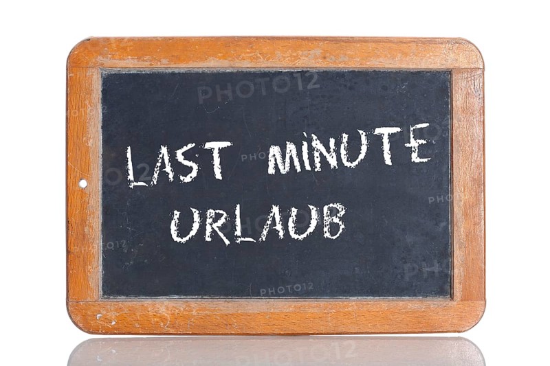 Old school blackboard with the words LAST MINUTE URLAUB