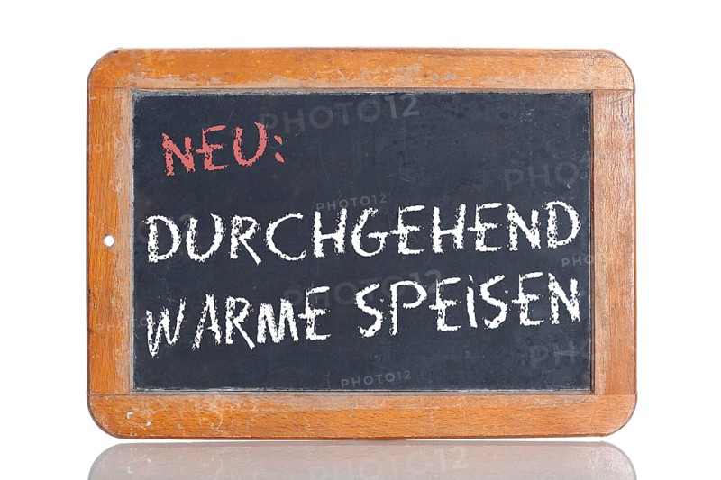 Old school blackboard with the words NEU: DURCHGEHEND WARME SPEISEN