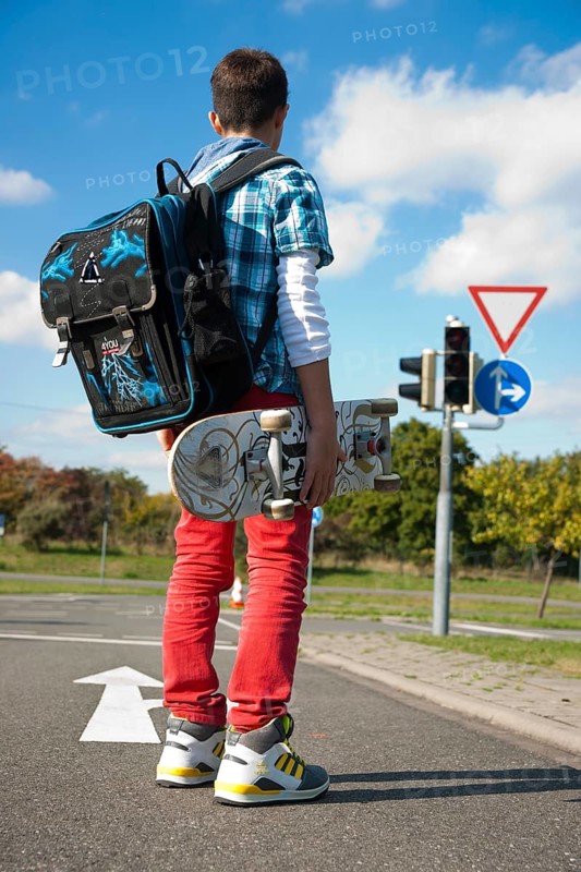 Boy with a school bag and a skateboard on a street