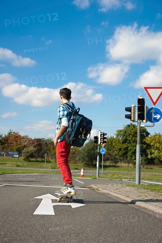 Boy with a school bag and a skateboard on a street