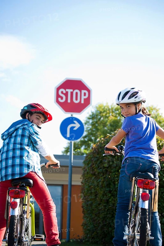 Boy and girl waiting with their bicycles in front of a stop sign