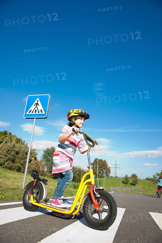 Girl crossing a zebra crossing with her scooter