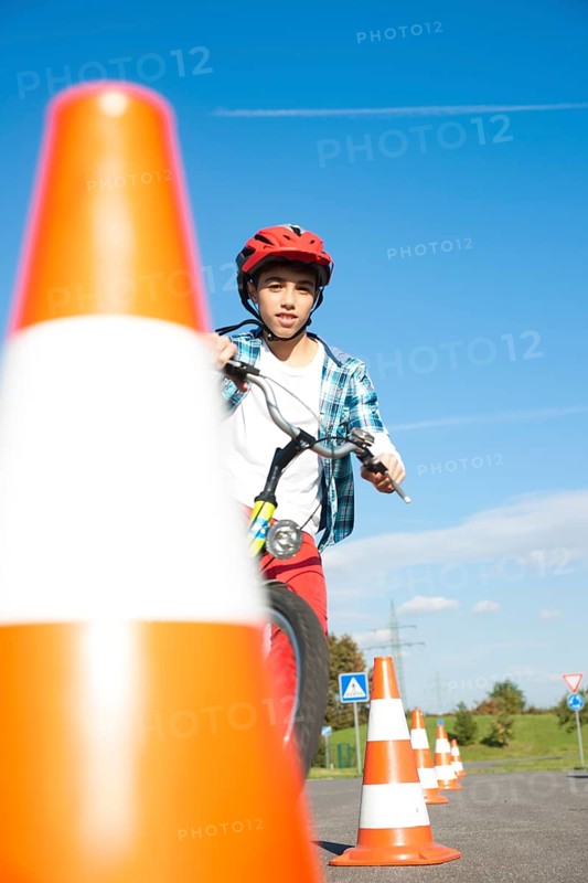 Child practicing to ride slalom on a bicycle at a traffic awareness course