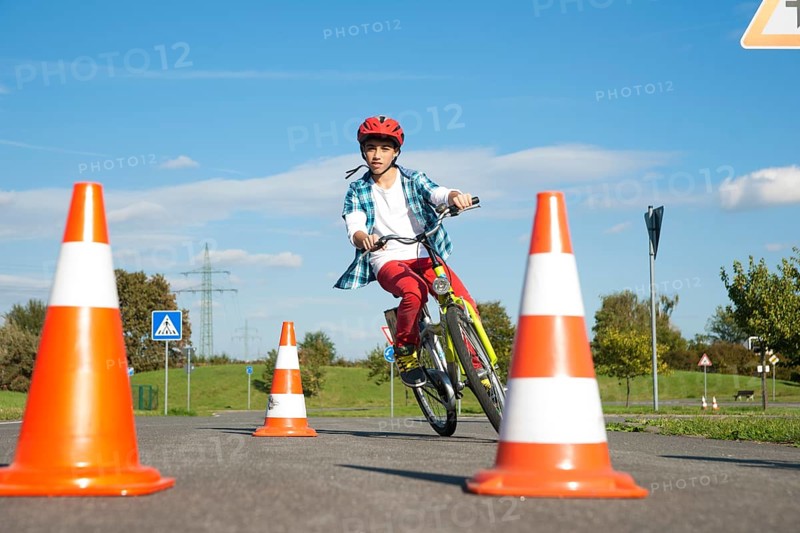 Child practicing to ride slalom on a bicycle at a traffic awareness course