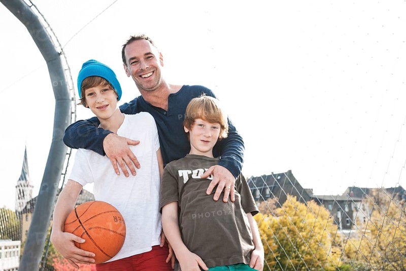 Two cool boys standing with their father on a playground