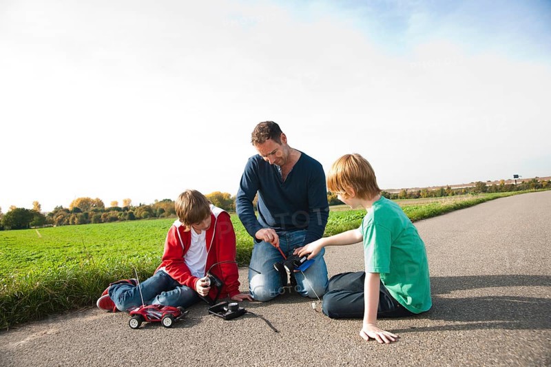 Father tinkering on a remote-controlled model car with his sons