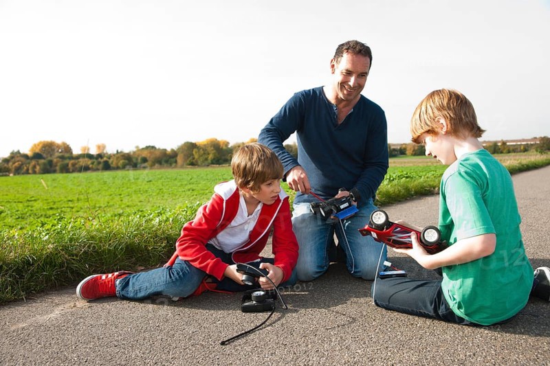 Father tinkering on a remote-controlled model car with his sons