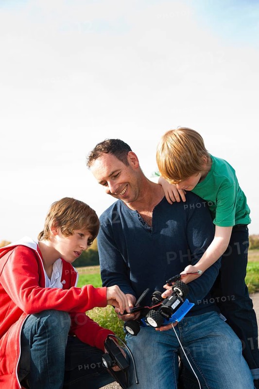 Father tinkering on a remote-controlled model car with his sons