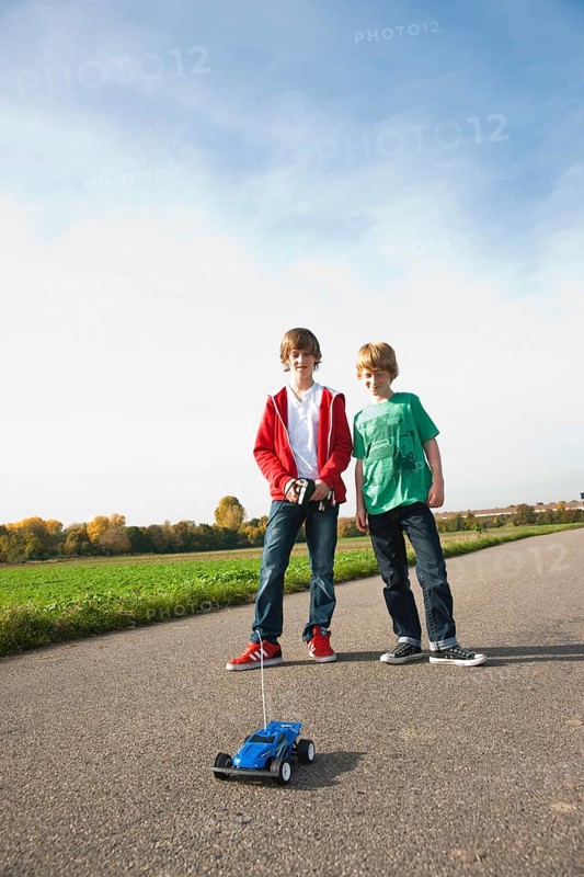Two boys playing with a remote-controlled model car