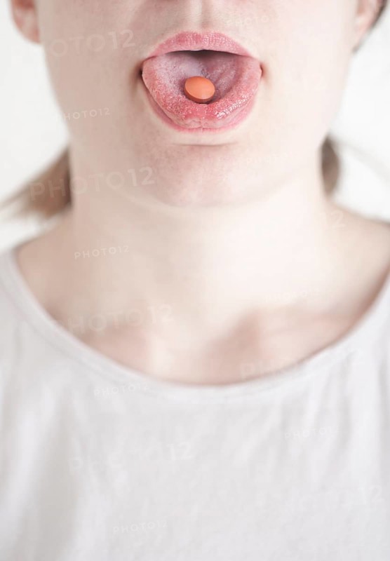 Woman with a pill on her tongue