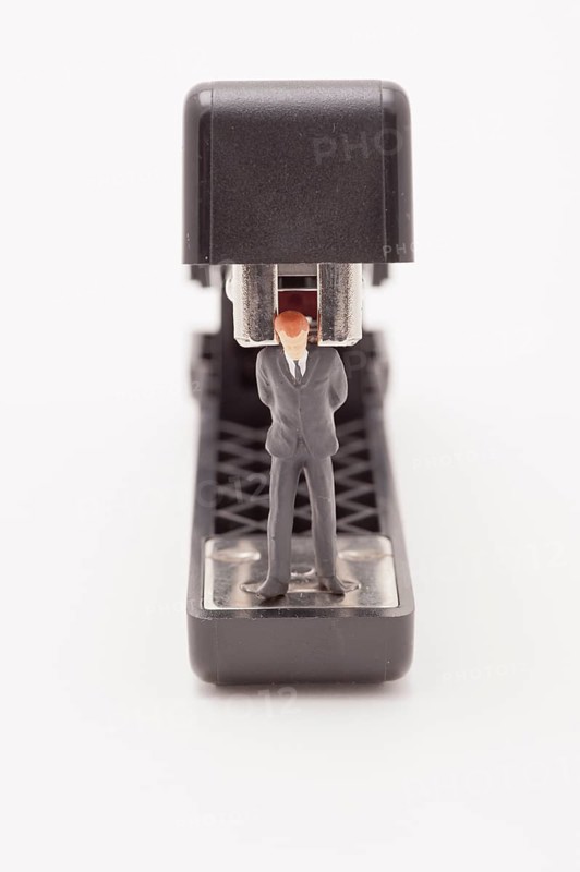 Figurine of businessman trapped by a stapler