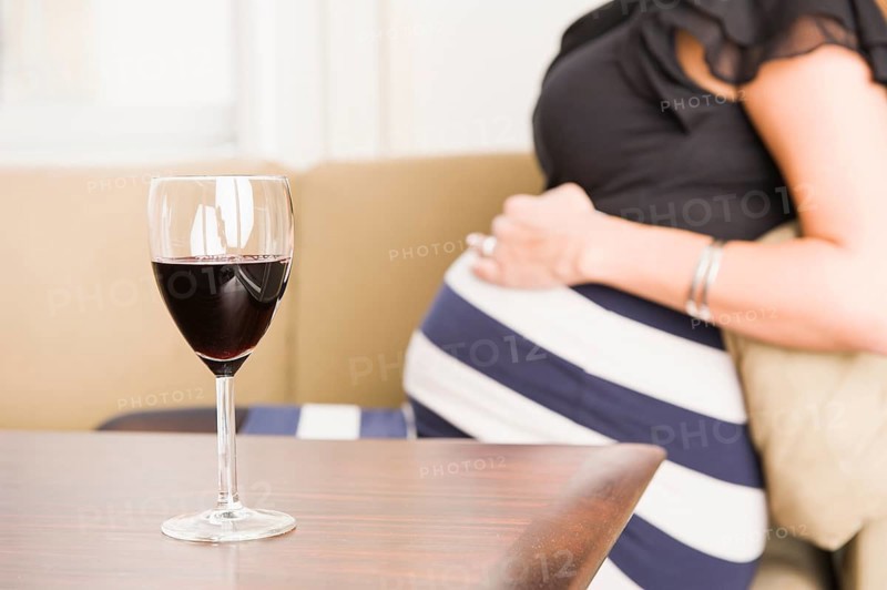 A glass of red wine and a pregnant woman