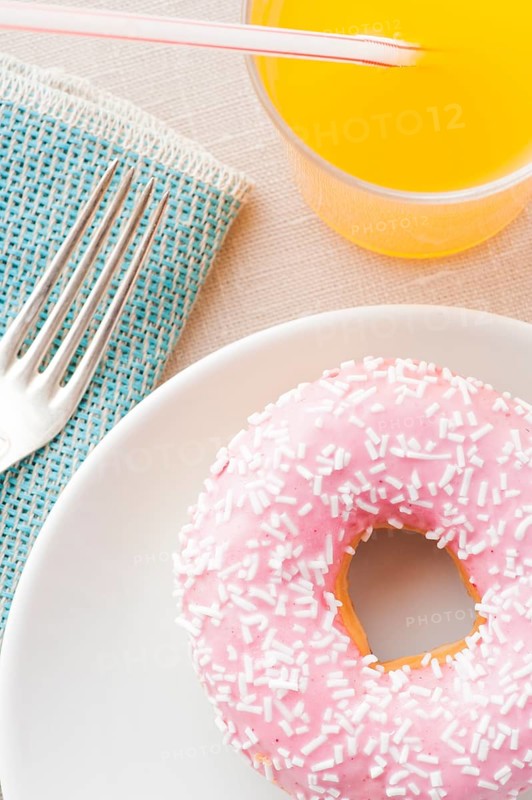 Donut with sprinkles and a glass of orange soda