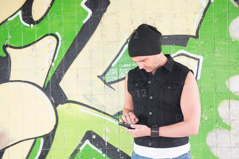 Man standing in front of wall covered with graffiti