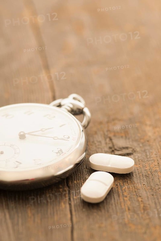 Two capsules next to retro pocket watch
