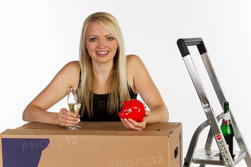 Young woman with a piggy bank and a moving box
