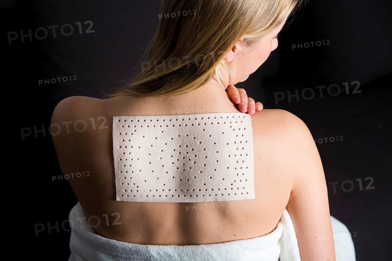 Young woman suffering from back pain has applied a heat plaster