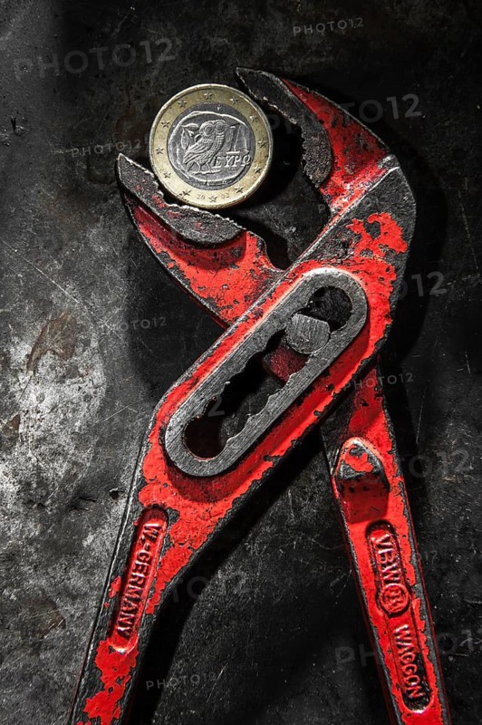 A Greek euro coin under pressure in a monkey wrench