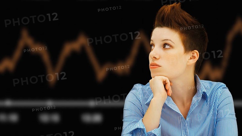 Business woman with a punk hairstyle in front of a stock exchange board