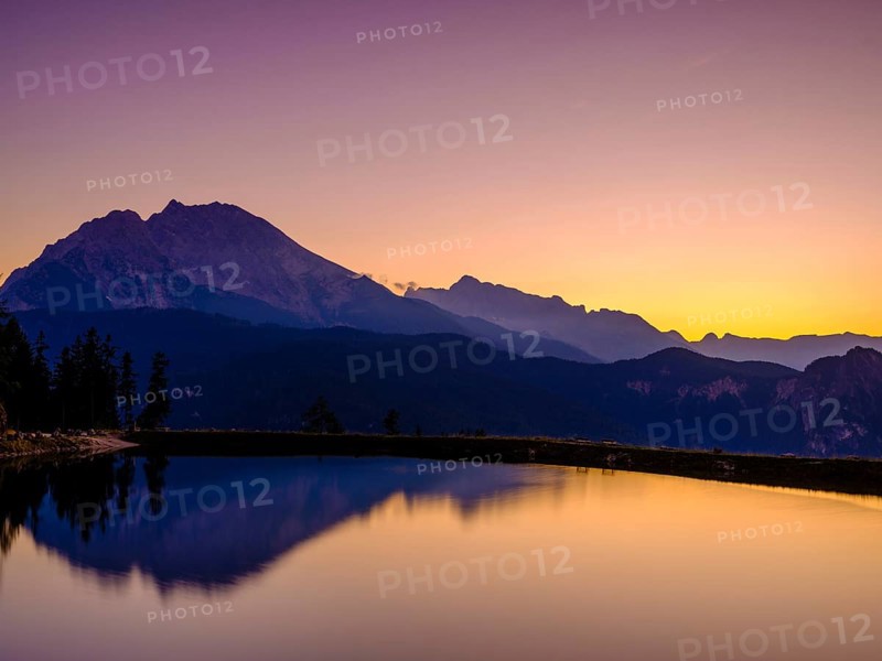 Mountain silhouettes reflected in an artificial mountain lake at sunset