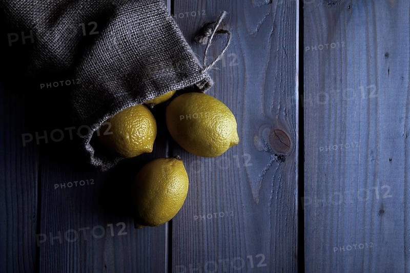 Lemons in a jute sack on wooden boards