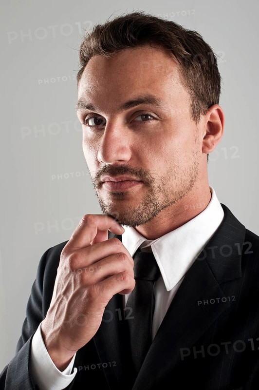 Young businessman wearing a suit with his hand on his chin