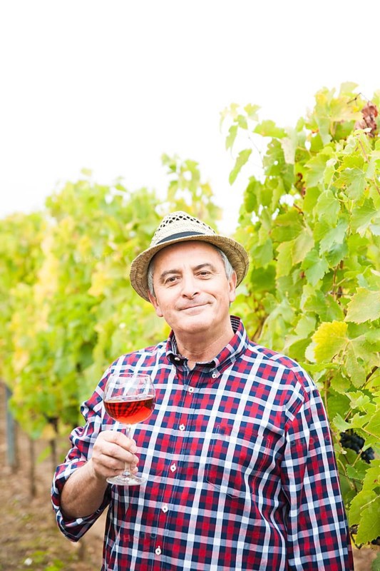 Winemaker or vintner standing with a glass of red wine in his vineyard