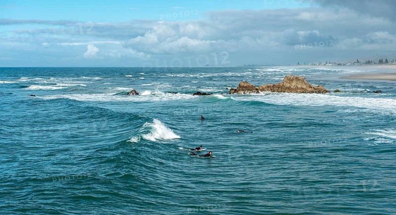 Surfers in the water at the coast near Mount Manganui