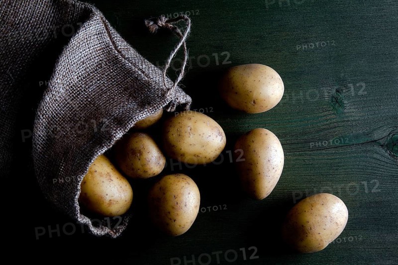 Potatoes in burlap sack on wood