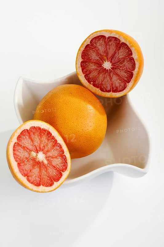 Ruby grapefruit cut open in porcelain bowl