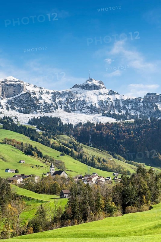 Green pastures in Appenzellerland with the community of Bruelisau and the snow-capped Appenzell Alps