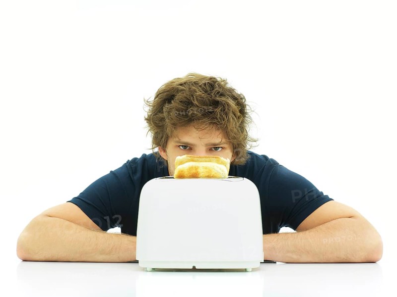 Young man behind a toaster with slices of toast