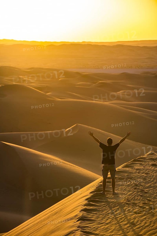 Man enjoying the sunset in the giant sanddunes of the Sahara