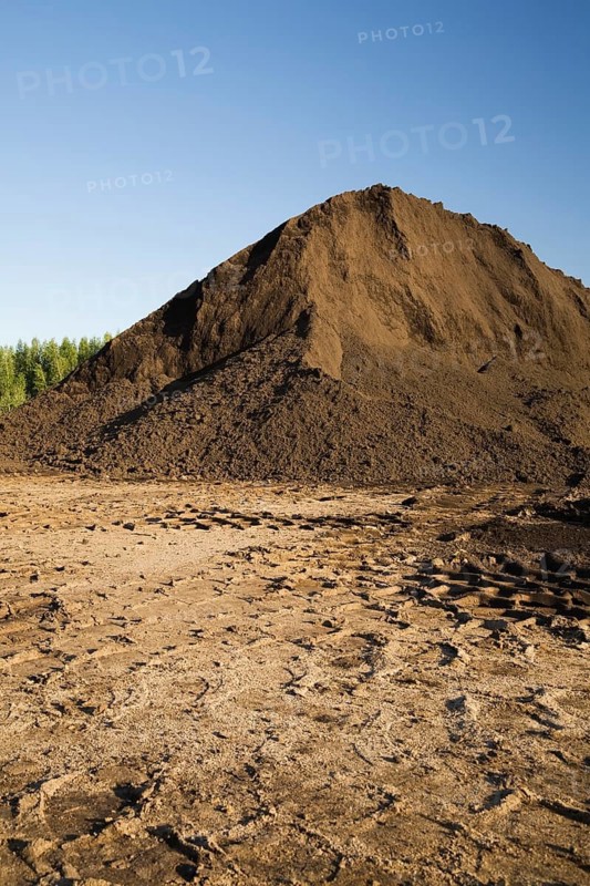 Heavy tire tracks and a mound of topsoil in a commercial sandpit