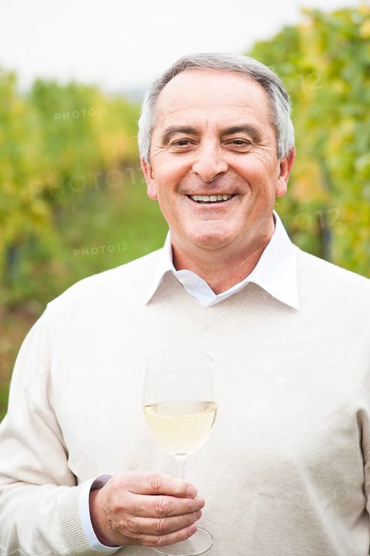 Winemaker or vintner holding a glass of wine in his vineyard