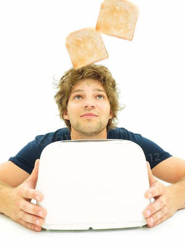 Young man looking at slices of toast as they pop out of a toaster