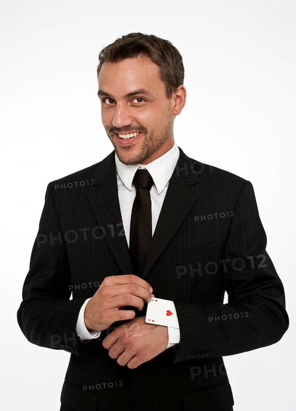 Man wearing a suit pulling an ace of hearts out of his sleeve