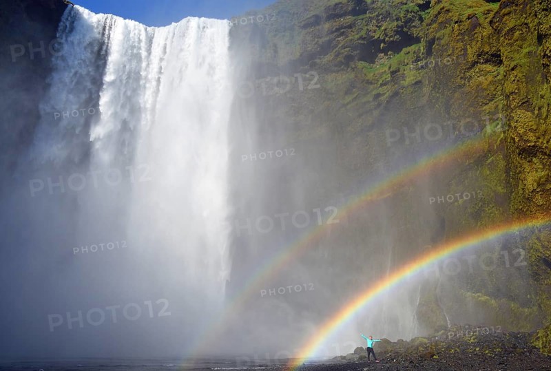 Man stands under double rainbow at the big waterfall Skogafoss