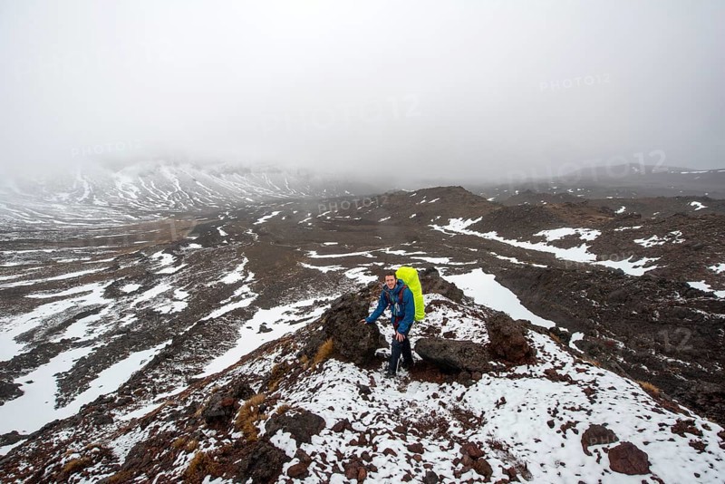 Hikers on hiking trail Tongariro Alpine Crossing in snow over lava fields