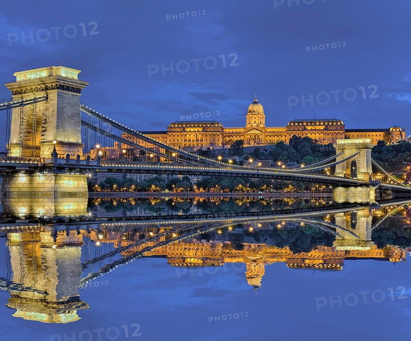 Chain bridge in front of castle palace with reflection in the Danube