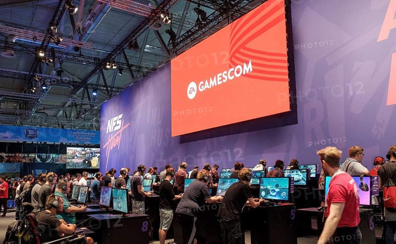 Visitors play video games under the gamescom logo at gamescom